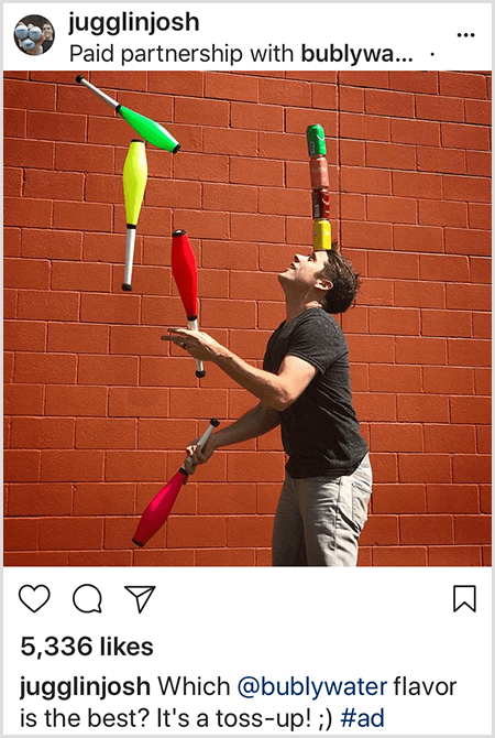 Džošs Hortons žonglē ar nūjām, kas atbilst četrām uz galvas sakrautajām Bubly ūdens kannām. Fons ir sarkanu ķieģeļu siena. Fotoattēls ir Džoša reklāma, kas izveidota Bubly ūdenim un ievietota savā Instagram plūsmā ar aprakstu, kurš Bubly ūdens aromāts ir labākais? Tas ir Toss Up!